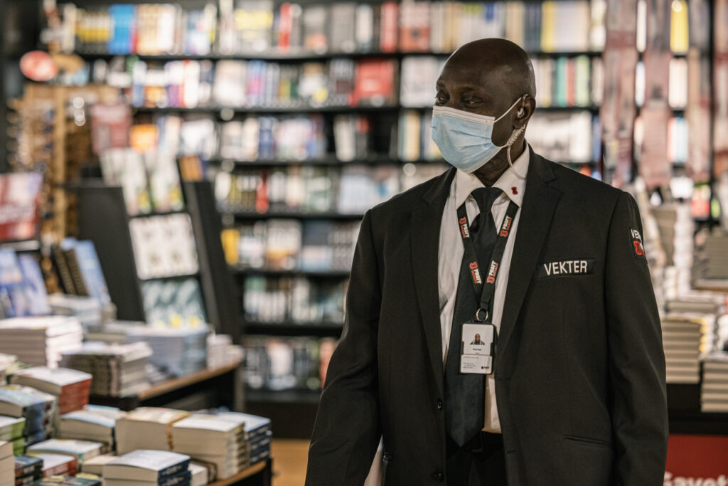 Vekter med maske i en bokhandel, mange bøker rundt han